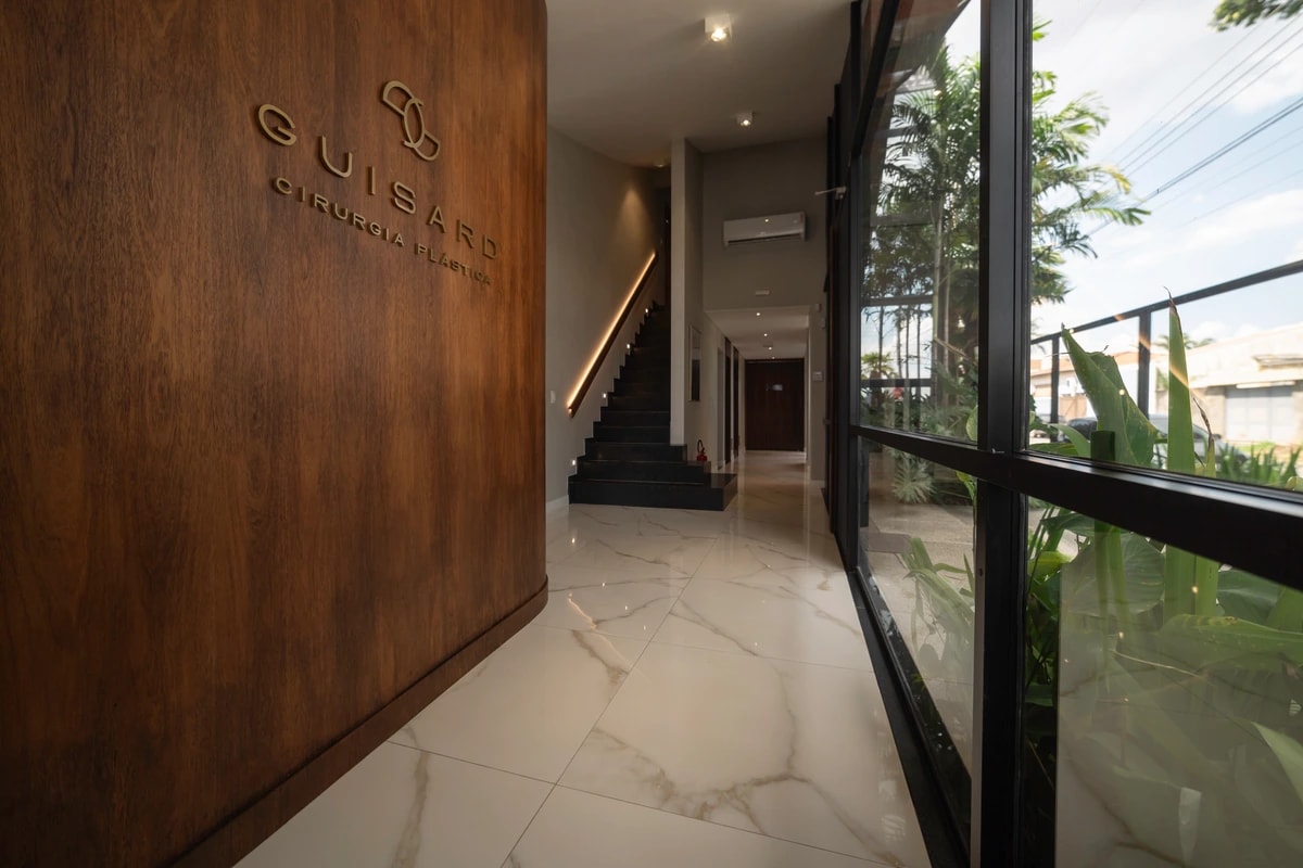 Hall de entrada com a marca Guisard aplicada na madeira e a escada ao fundo