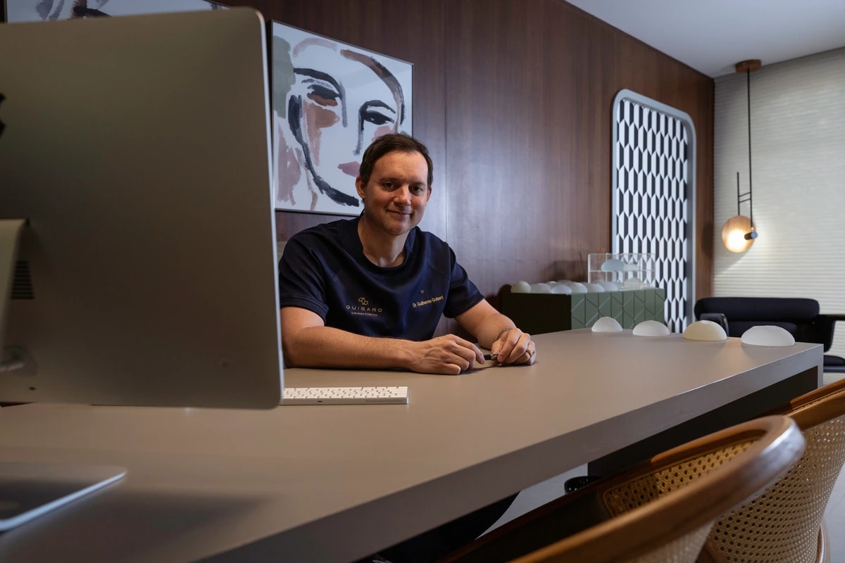 Sala de consulta do Dr. Guilherme Guisard, com mesa ampla e obras de arte na parede